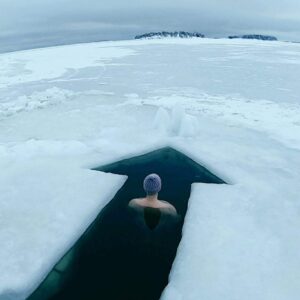 Henkilö istuu avannossa jääkentän keskellä talvimaisemassa – pysähtymisen ja luottamuksen hetki uudenvuodenlupauksen tueksi